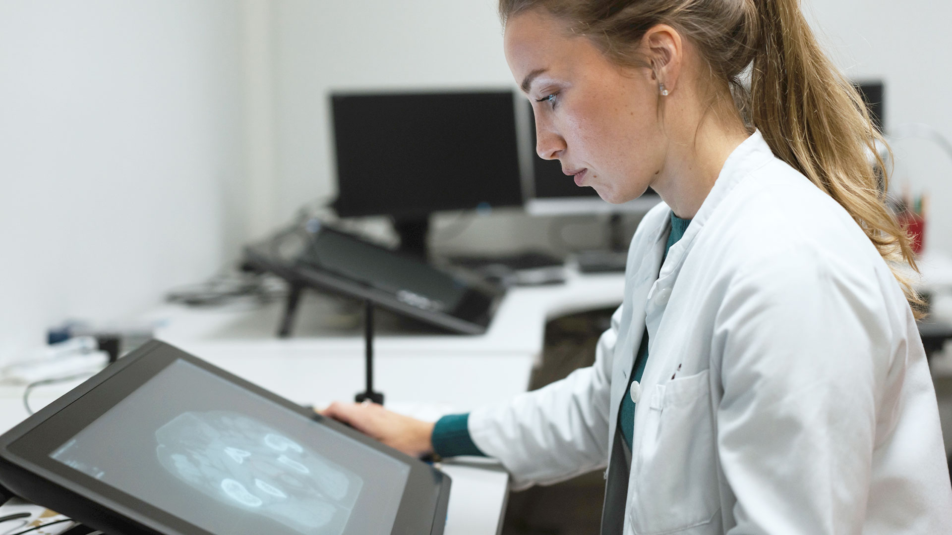 A doctor is sitting at her desk looking at contours on her computer screen. Next to this image is the text "A Clinical Evaluation of MVision AI's Contour+ Models"