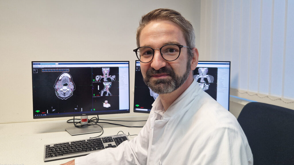 Christoph Dumke sitting at this desk with contoured images on computer screens
