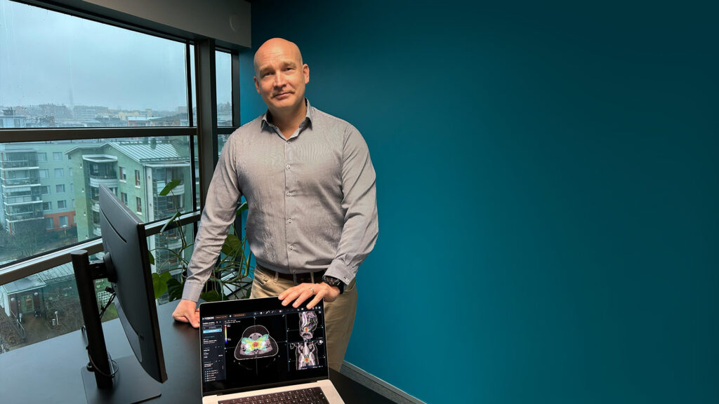 Dr. Kiljunen standing at a desk, hands placed on a laptop